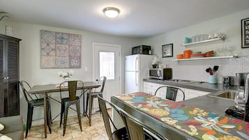 Una cocina con comedor, que incluye un refrigerador, microondas y varios electrodomésticos.