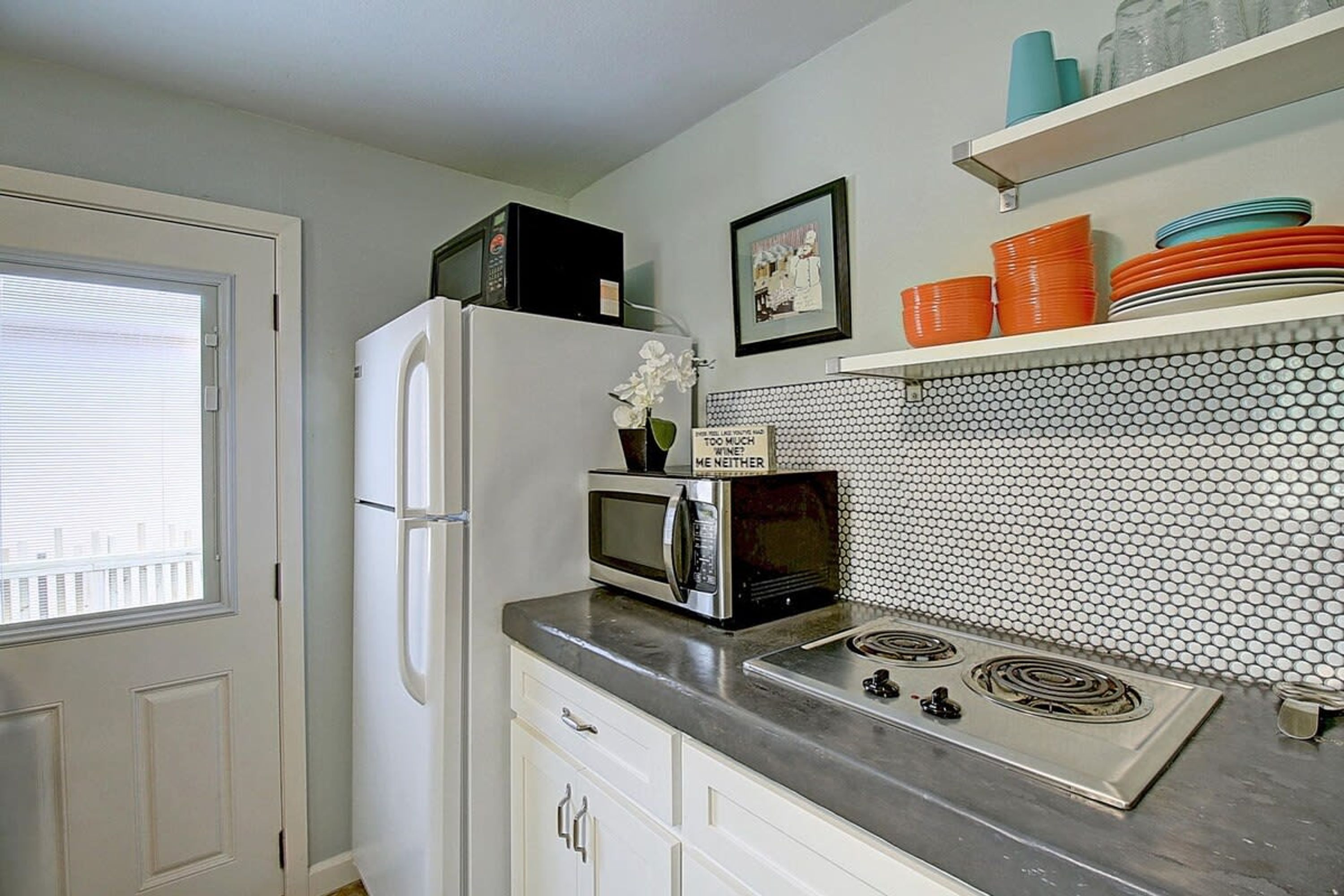 A kitchen with a refrigerator, microwave, stove, and a tiled backsplash.