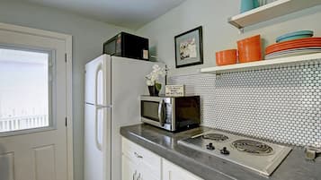 Cozinha equipada com geladeira, micro-ondas, fogão e painel de azulejos.