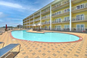 A hotel with a swimming pool surrounded by a tiled deck, multiple balconies, and outdoor seating. - Incredible Ocean Views Direct Beach Access Pool (Port Aransas)