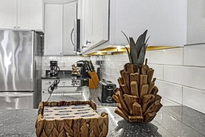 A kitchen with white cabinets, stainless steel appliances, and a wooden cutting board and knife block on the counter. - Incredible Ocean Views Direct Beach Access Pool (Port Aransas)