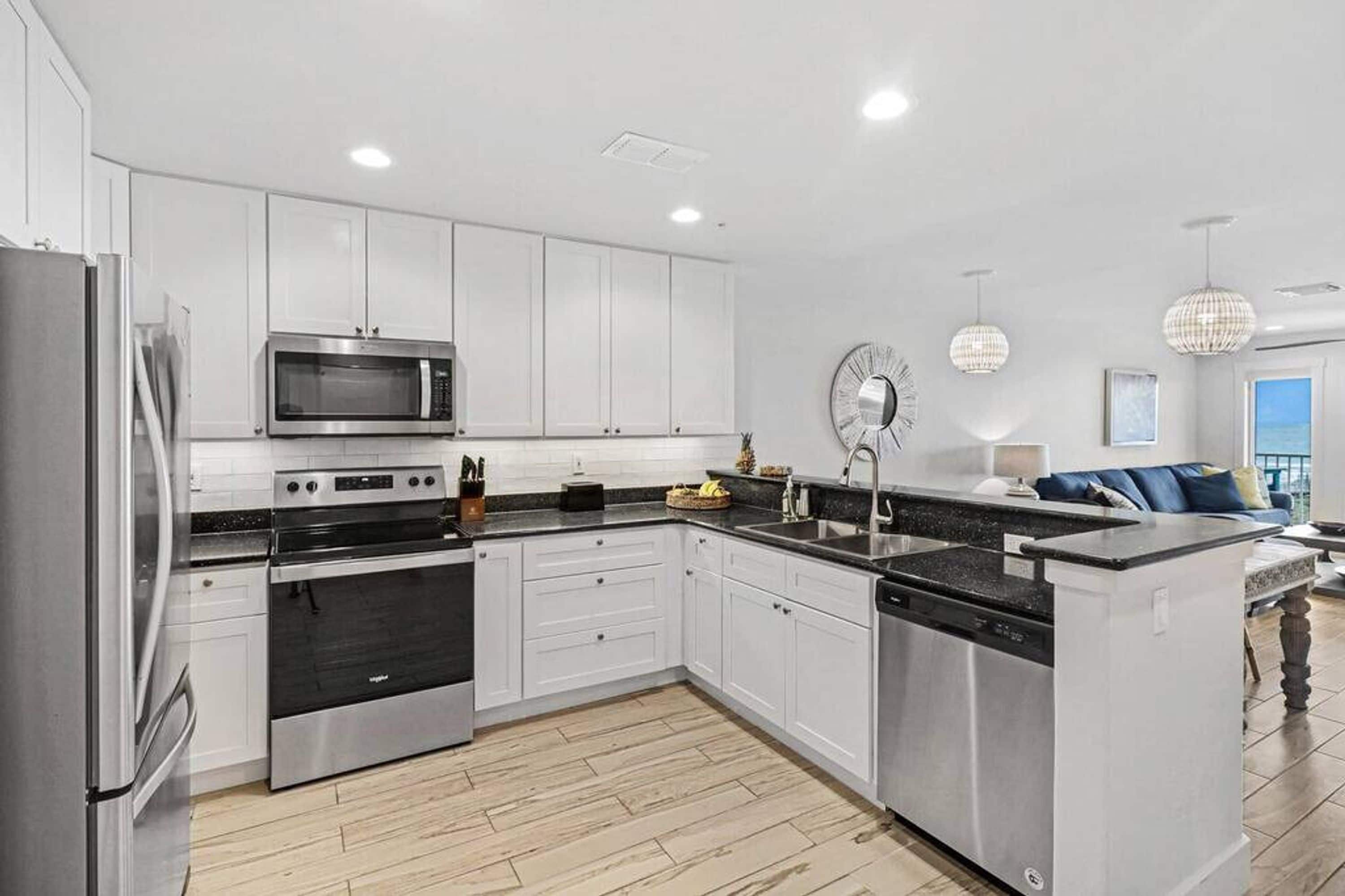 A modern kitchen with white cabinetry, stainless steel appliances, and a central island with a sink.