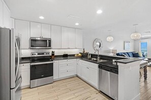 Uma cozinha moderna com armários brancos, eletrodomésticos de aço inoxidável e uma ilha central com pia.