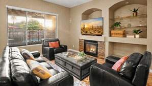 A living room with a fireplace, leather sofas, a coffee table, and a television. - Movie Theater Pool Arcade Fire Pit (Glendale)