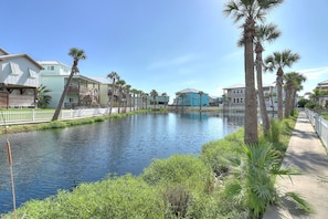 A canal with houses on one side and a sidewalk on the other. - Paradise Vibes- Pond Views 2 Balconies (Port Aransas)