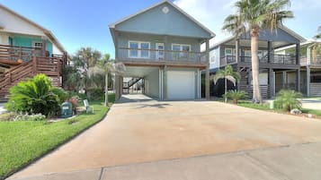A two-story residential building with a covered front porch, a garage, and a landscaped driveway.