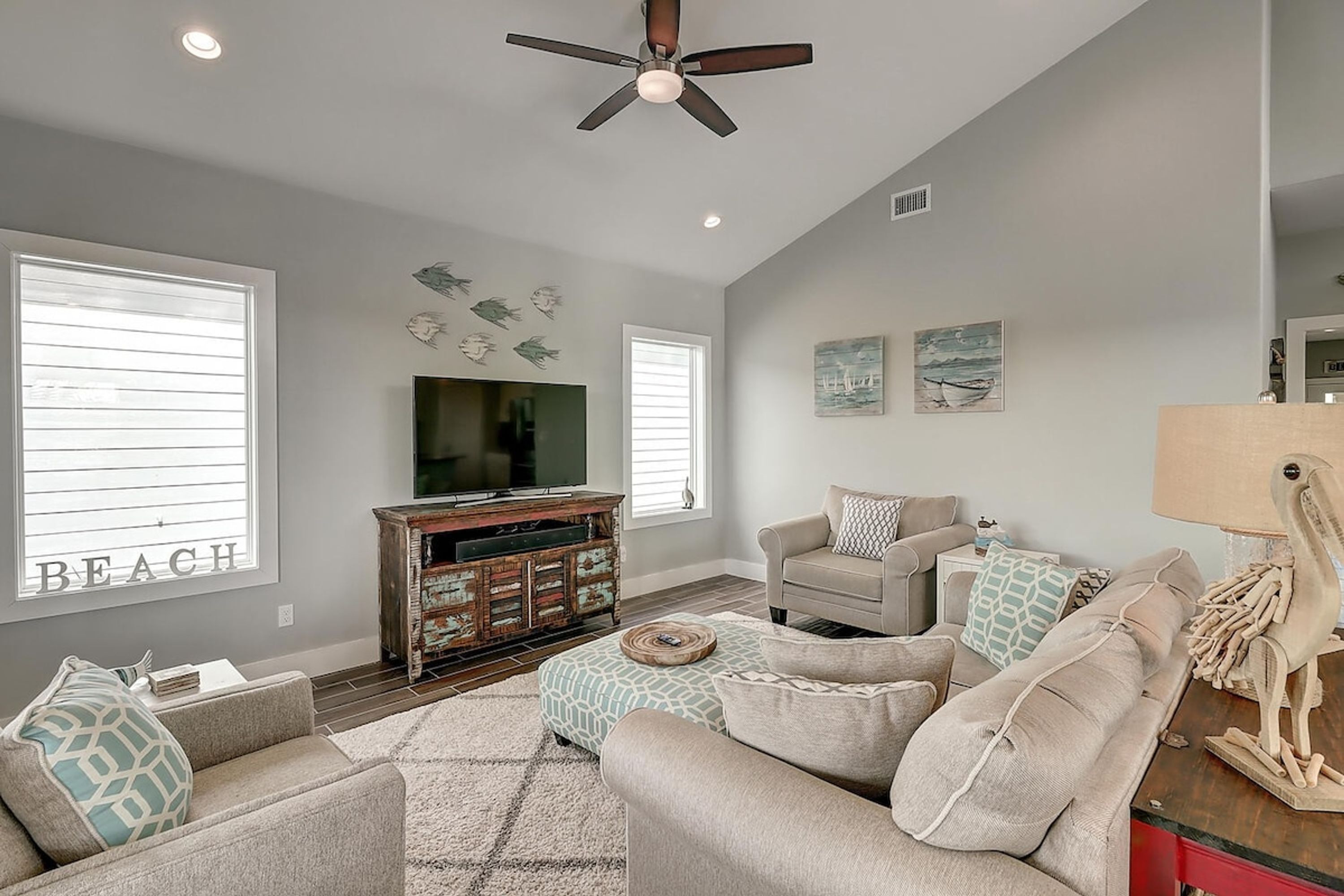 A living room with a ceiling fan, a television, a sofa, and decorative wall art.