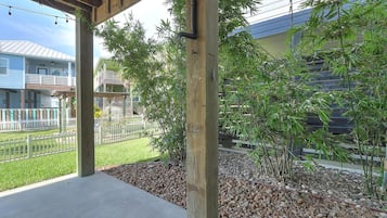 A covered outdoor area with a concrete floor, wooden pillars, and a bamboo plant.