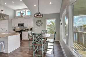 A spacious kitchen with white cabinetry, a central island, and a dining area with mismatched chairs. - Paradise Vibes- Pond Views 2 Balconies (Port Aransas)