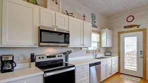 A kitchen with white cabinets, a microwave, stove, dishwasher, and a sink. - Sweet Home La Cabana Patio BBQ Community Pool (Port Aransas)