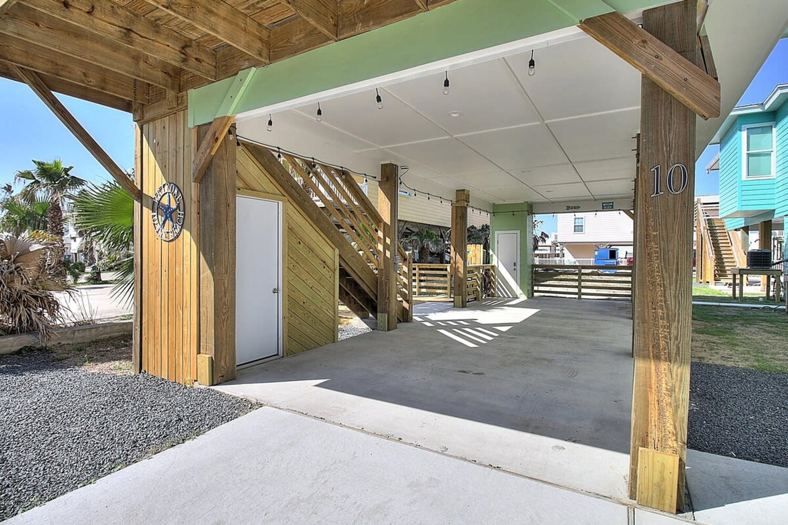 A covered outdoor area with a wooden structure, a door, and a staircase leading to a higher level.