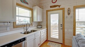 A compact kitchen with a dishwasher, a toaster, and a wooden door. - Sweet Home La Cabana Patio BBQ Community Pool (Port Aransas)