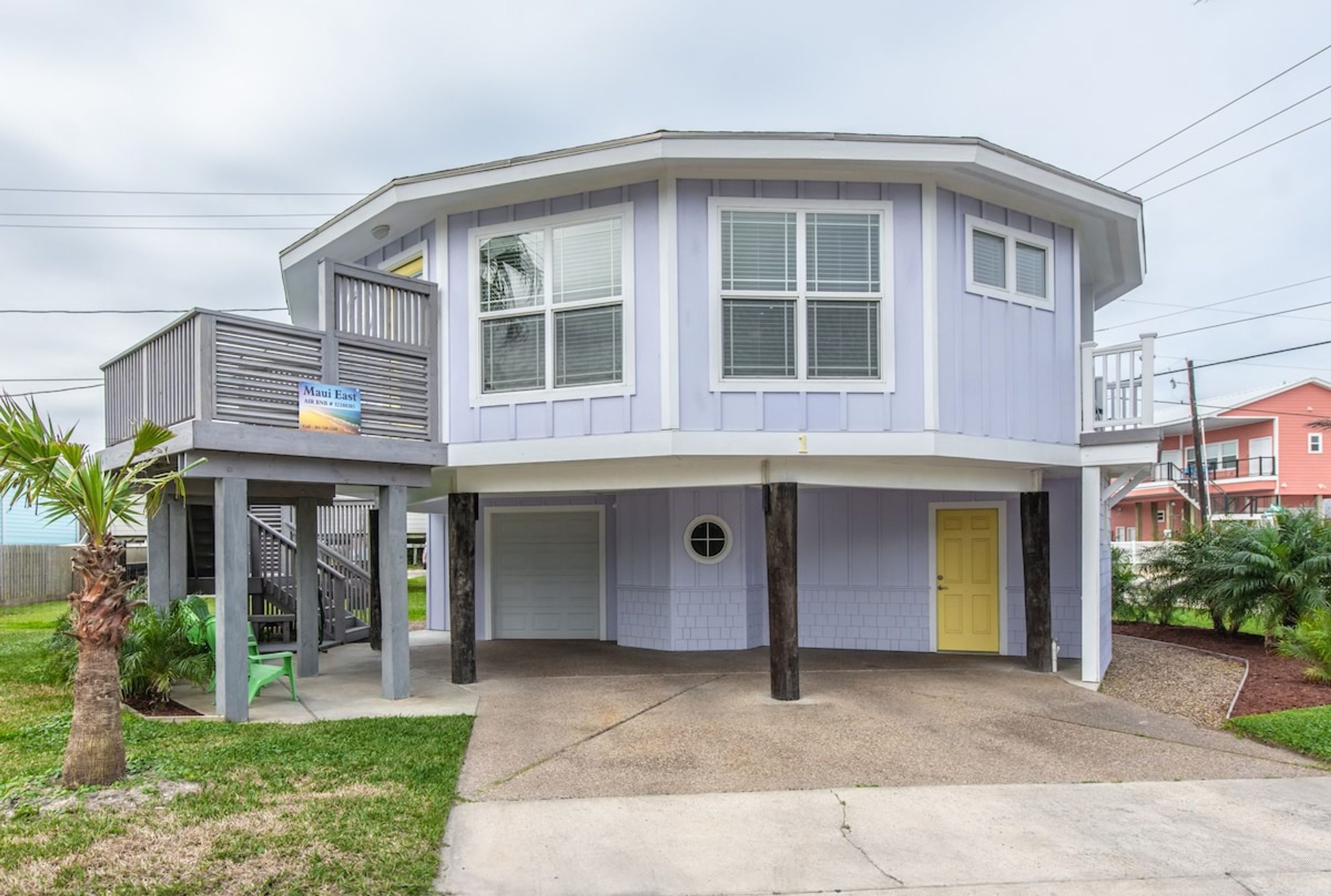 Ein zweistöckiges Haus mit Garage, überdachter Veranda und einer kleinen Sitzgelegenheit im Freien.
