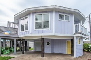 Ein zweistöckiges Haus mit verdeckter Veranda, einer Garage und einer kleinen Terrasse mit Sitzgelegenheiten.
