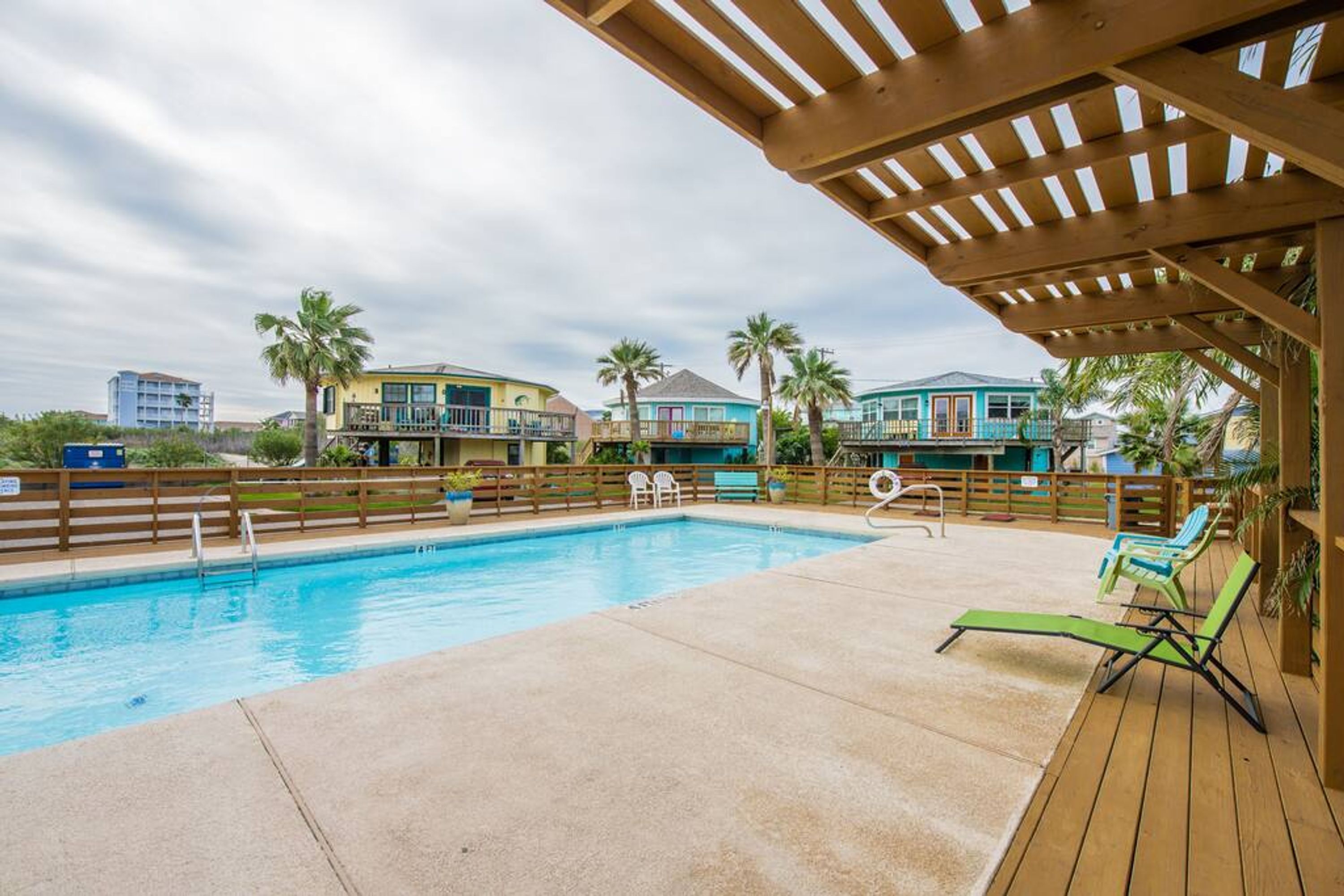 Ein Pool mit Holzterrasse und Liegestühlen.