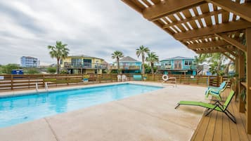 A swimming pool with a wooden deck and lounge chairs.