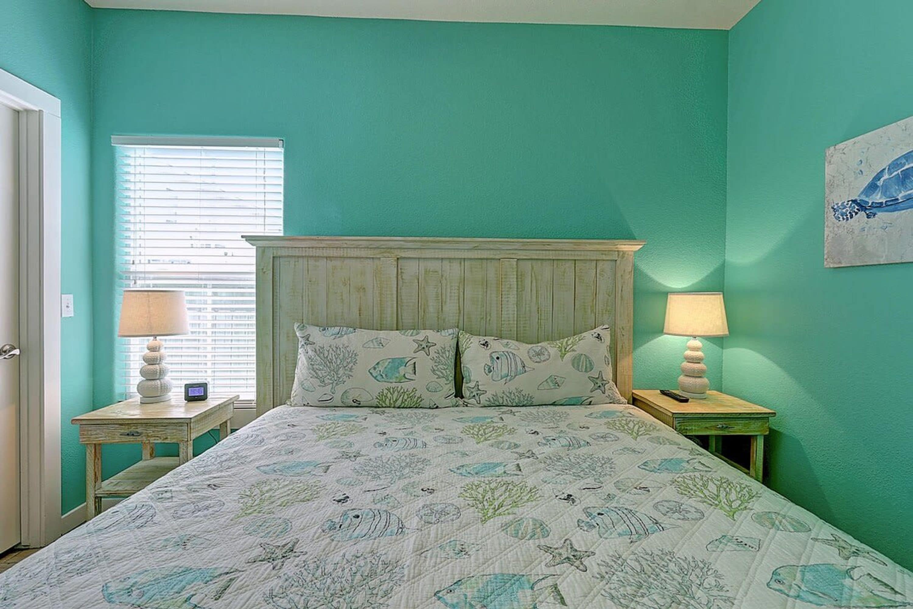 Une chambre à coucher avec un lit, deux tables de chevet, une fenêtre avec des stores et un tableau au mur.