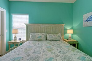 Une chambre à coucher avec un lit, deux tables de chevet, une fenêtre avec des stores et un tableau au mur.