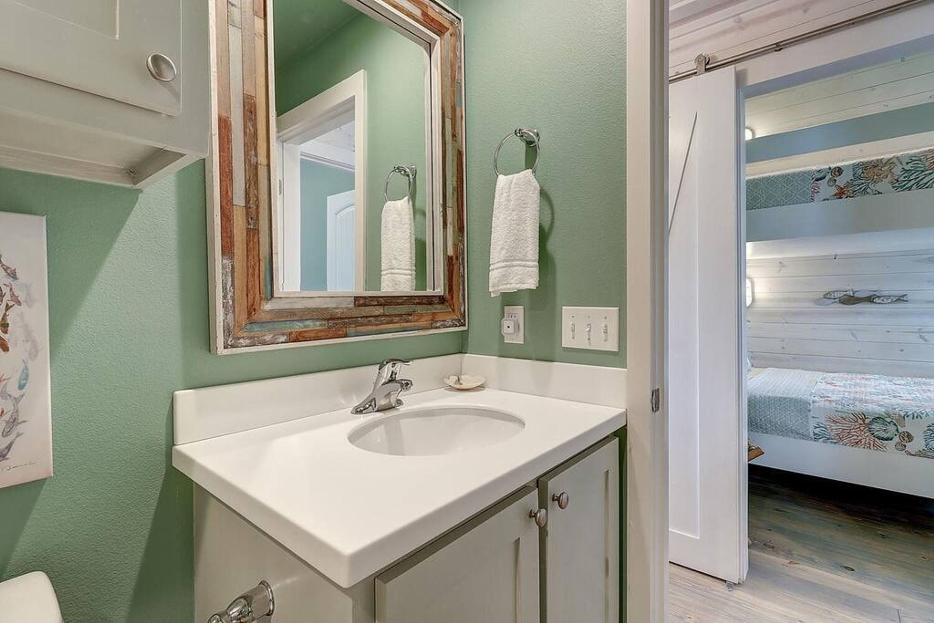 A bathroom with a white sink, a mirror with a wooden frame, and a towel hanging on the wall.