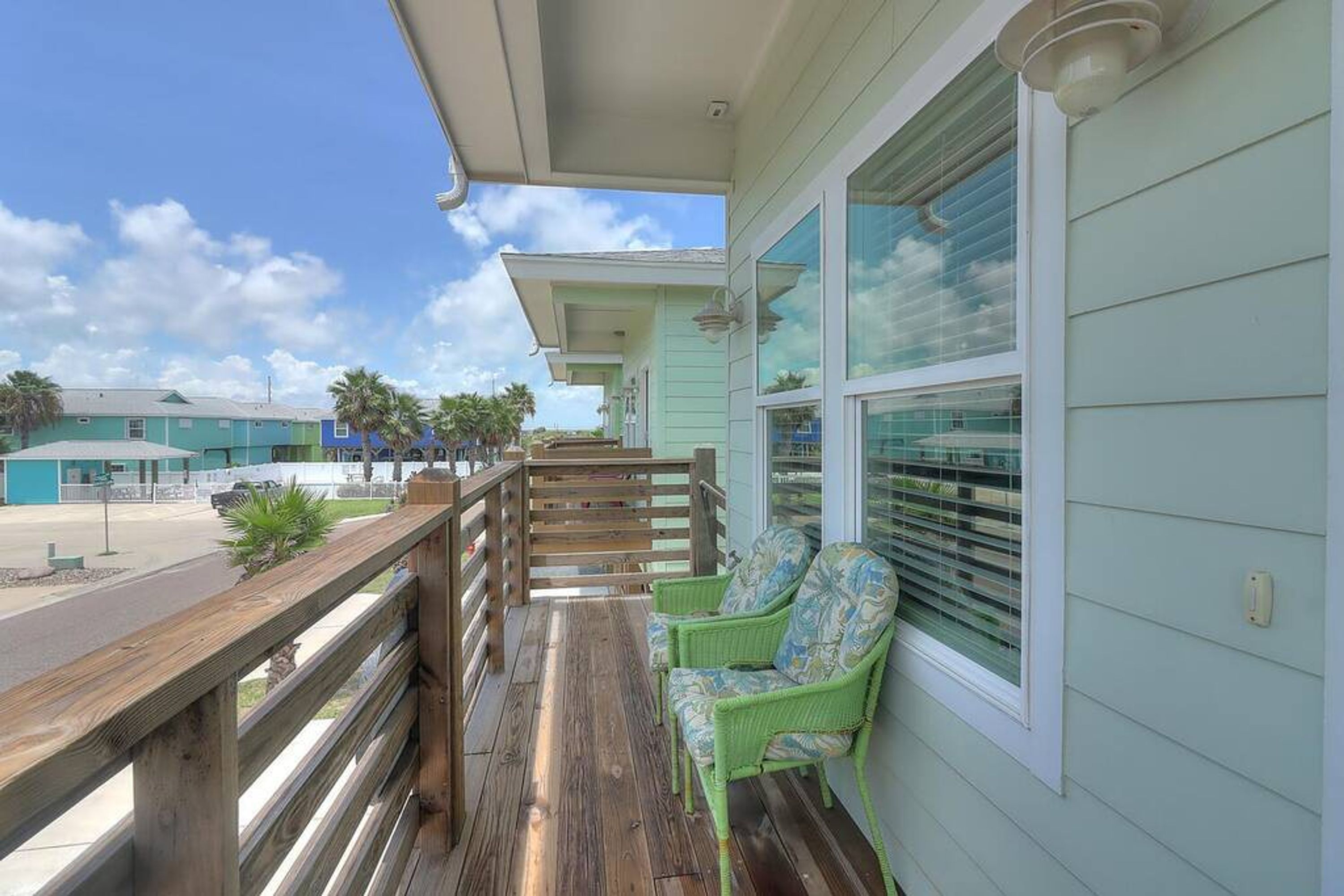 A wooden deck with a railing, a covered area, and a seating area with a chair.