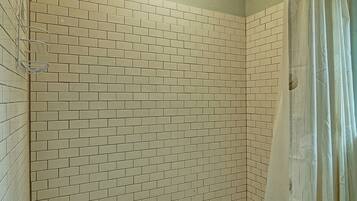 Baño con paredes de azulejos tipo metro y cortina de ducha.