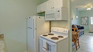 A compact kitchen with a refrigerator, microwave, and stove. - Captains Quarters Large Pool Boardwalk to Beach (Port Aransas)
