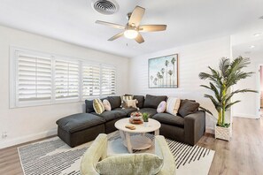 Ein modernes Wohnzimmer mit einer Eckcouch, einem runden Couchtisch und einem Deckenventilator.