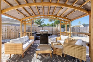 A covered outdoor patio with a barbecue grill, wicker furniture, and a wooden fence. - Deerfield Beach 10 min 2 Beach Hot Tub Pool Table (Deerfield Beach)