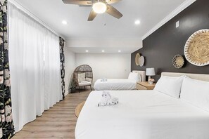 Ein Hotelzimmer mit einem Bett, einem Sessel, einem Nachttisch und einem Deckenventilator.