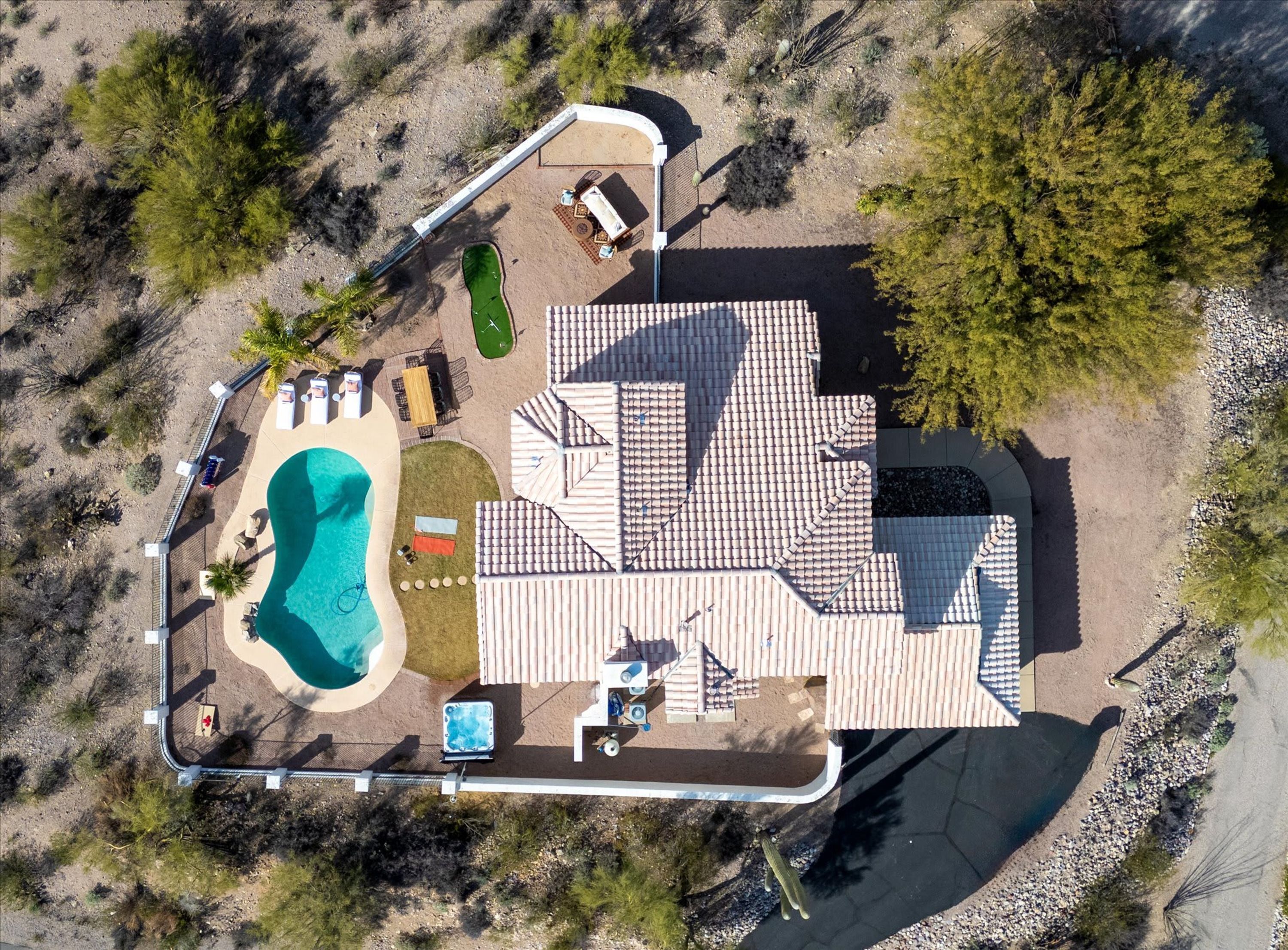 Vista aérea de una propiedad con piscina, zona de patio y un edificio grande con un diseño de techo único.