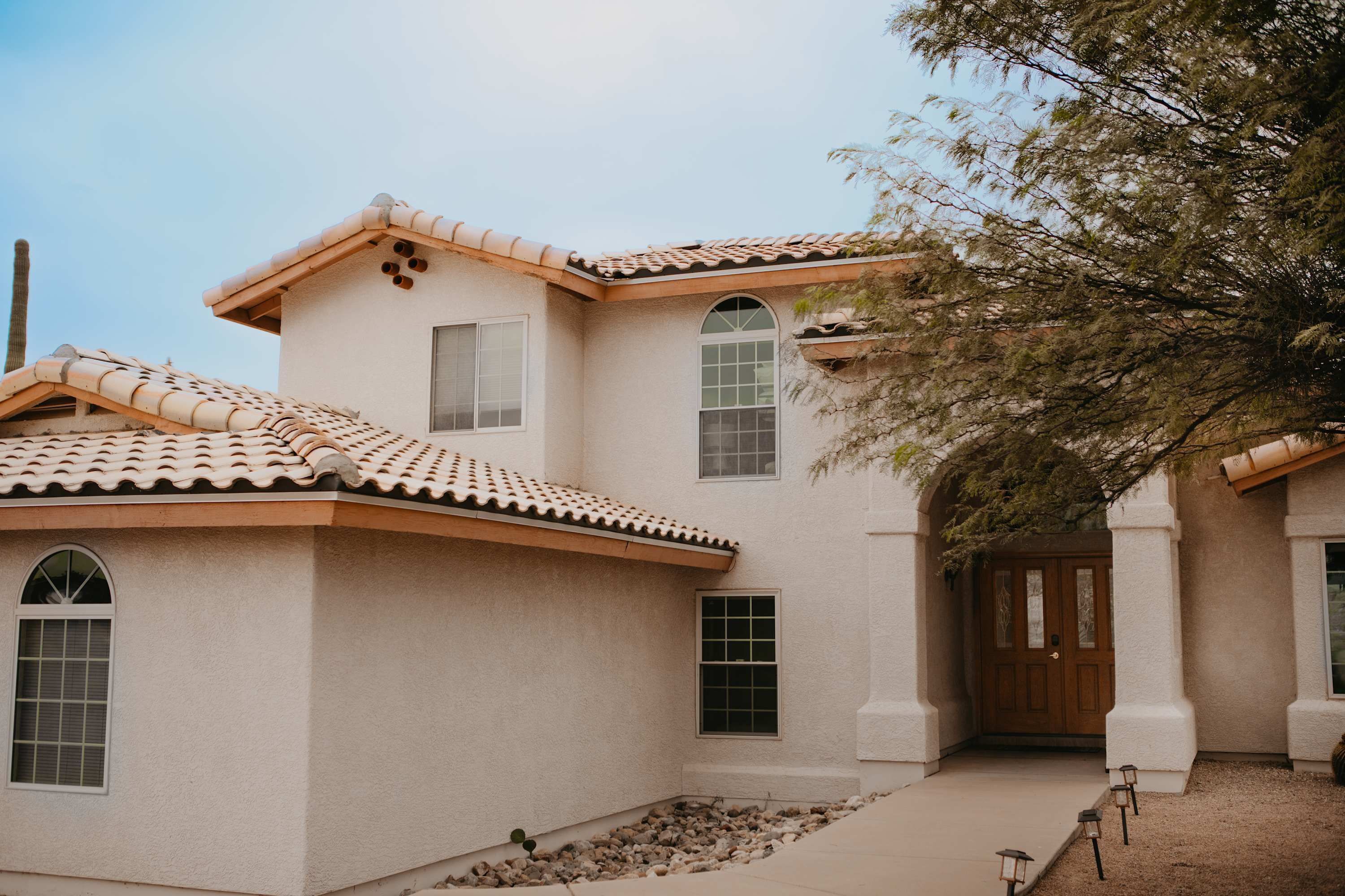 A two-story house with a tiled roof, multiple windows, and a front door.