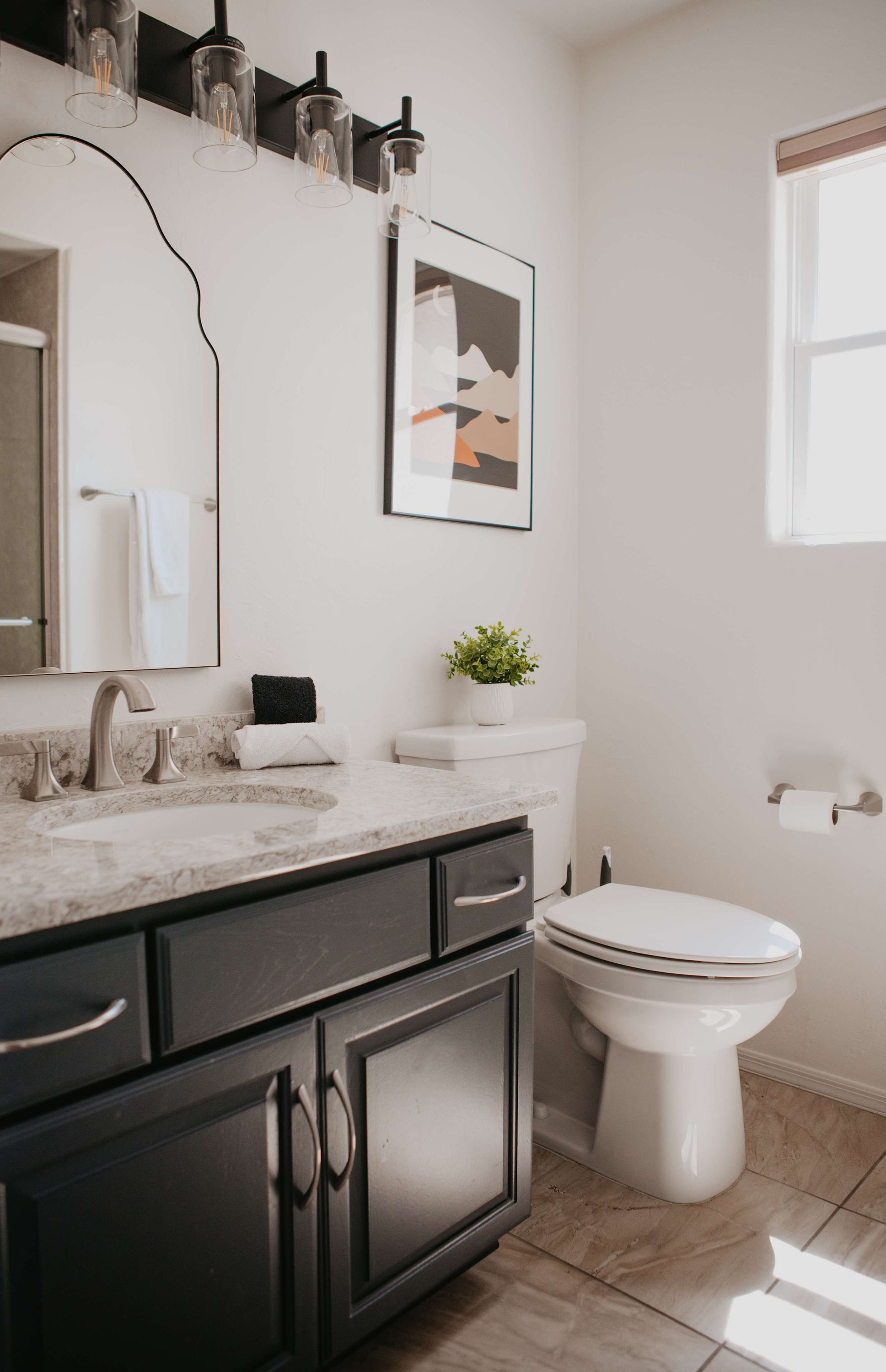 A bathroom with a marble sink, a toilet, and a framed picture on the wall.