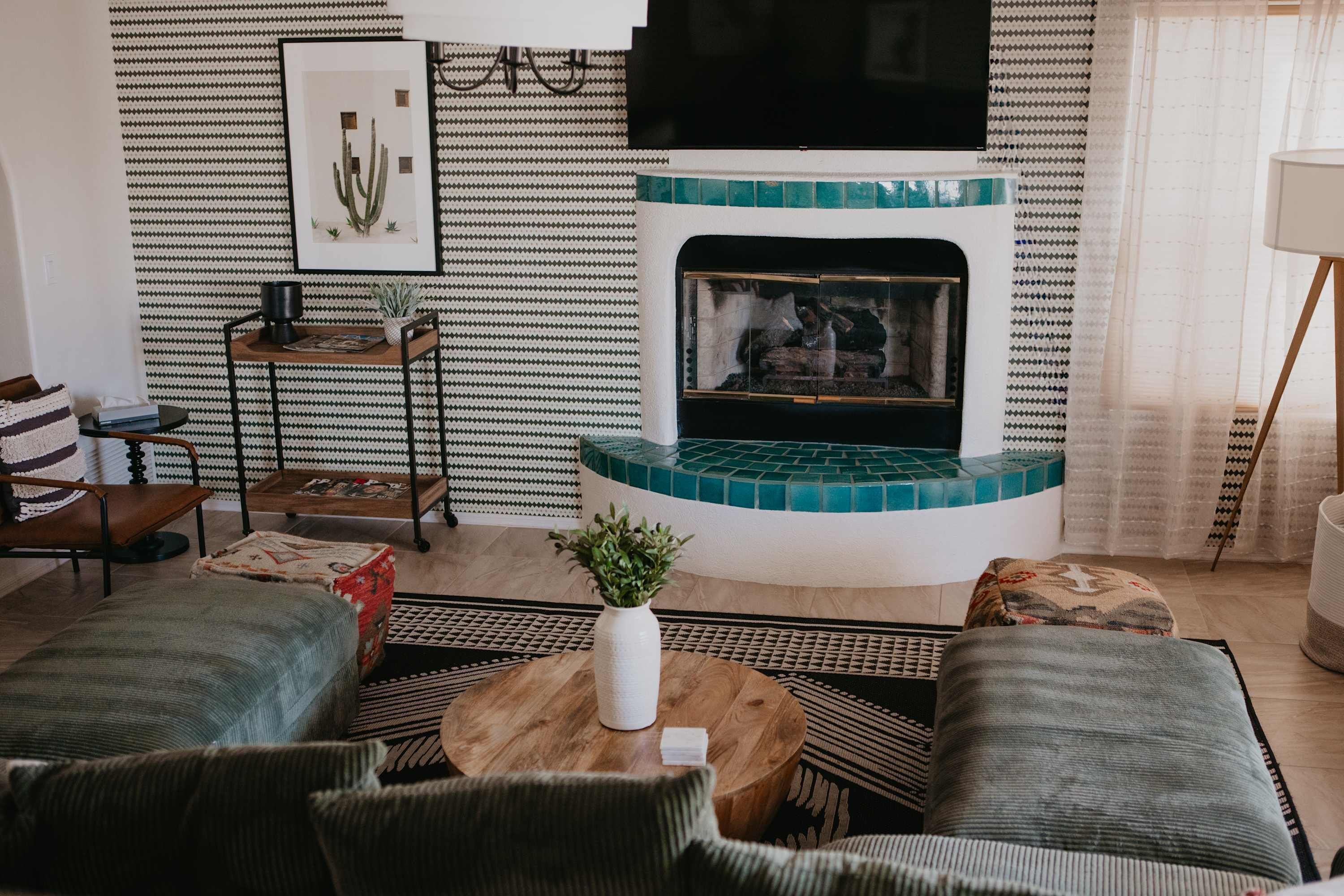 Una sala de estar acogedora con chimenea, papel tapiz decorativo y asientos cómodos.