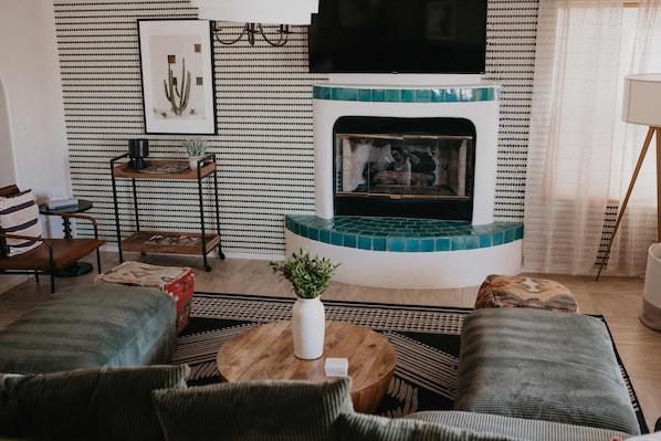 A cozy living room with a fireplace, patterned wallpaper, and comfortable seating. - Casa de Oro 360 Desert Views Pool Spa (Tucson)