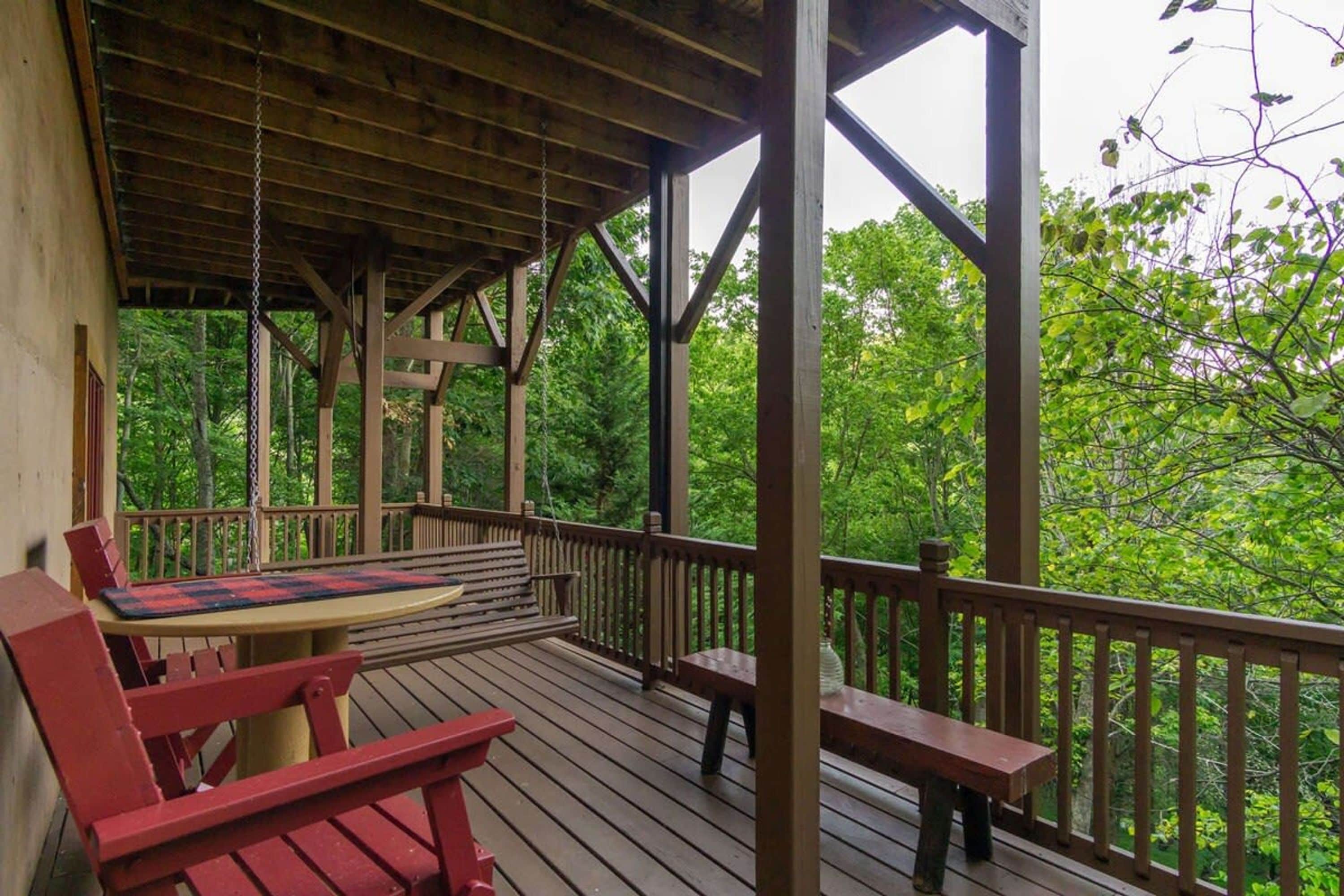 A wooden deck with benches and a table, surrounded by trees.