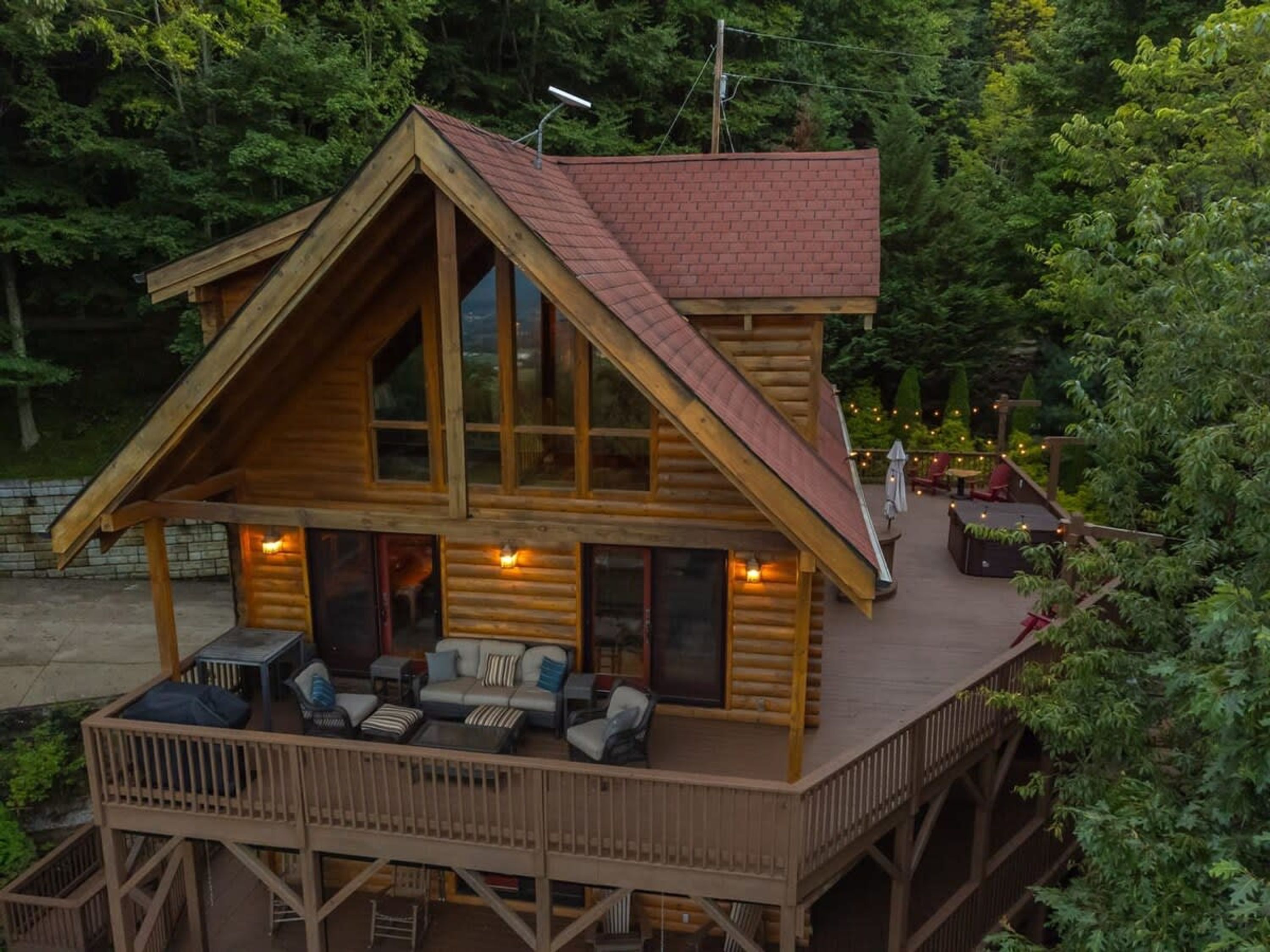 Une cabane en rondins dotée d’une terrasse, de meubles de jardin et d’une cheminée.