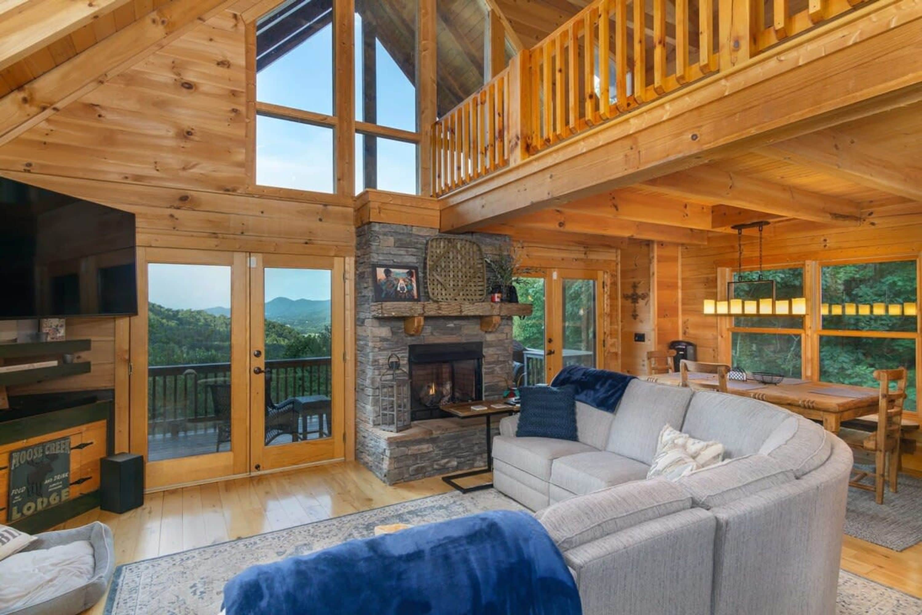 Une cabane spacieuse avec une cheminée en pierre, un grand canapé et un coin repas.