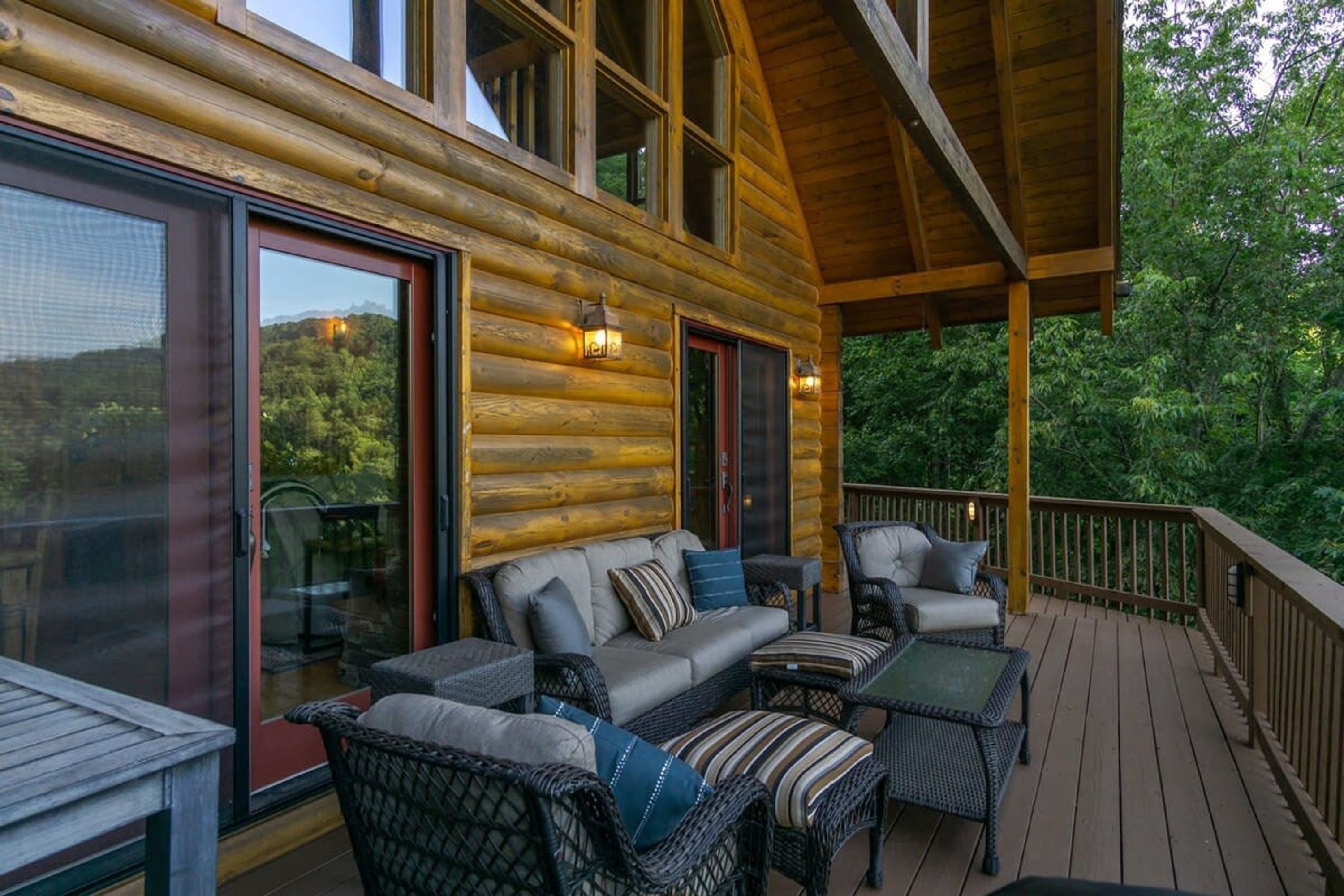 A log cabin with a deck, outdoor seating, and large windows.