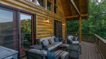 A log cabin with a deck, outdoor seating, and large windows.