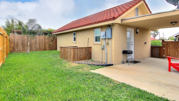 A single-story house with a red-tiled roof, a covered patio, and a fenced backyard. - Siesta Villa Private Patio Dog Friendly Cottage (Port Aransas)