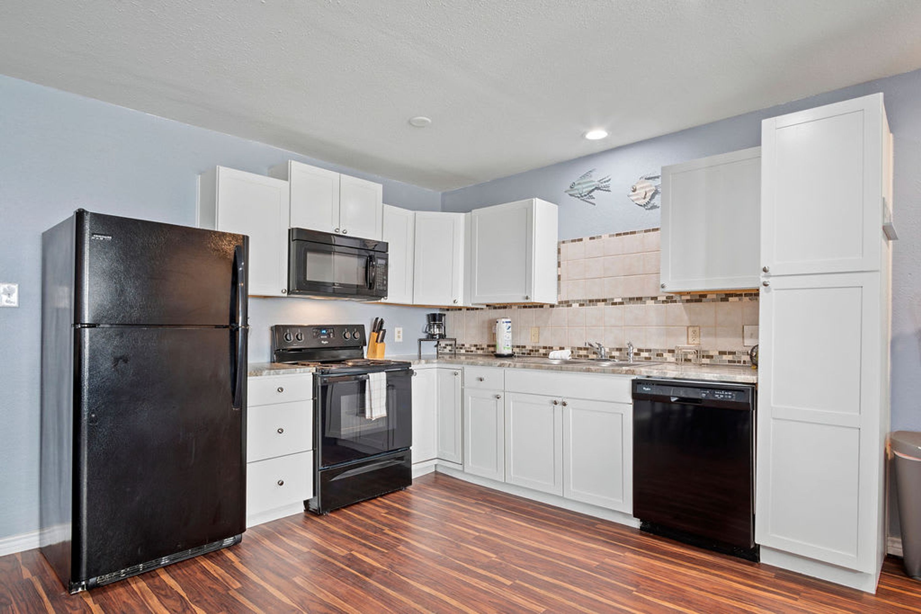 A kitchen with white cabinets, a black refrigerator, a microwave, an oven, and a dishwasher.