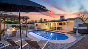 Un patio trasero con piscina, mobiliario exterior y un porche cubierto.