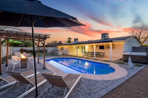 Ein Garten mit Schwimmbad, Gartenmöbeln und einer überdachten Terrasse.