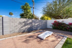 Eine Terrasse mit einer Betonmauer, einer weißen Bank und einem kleinen Garten mit roten Blumen.