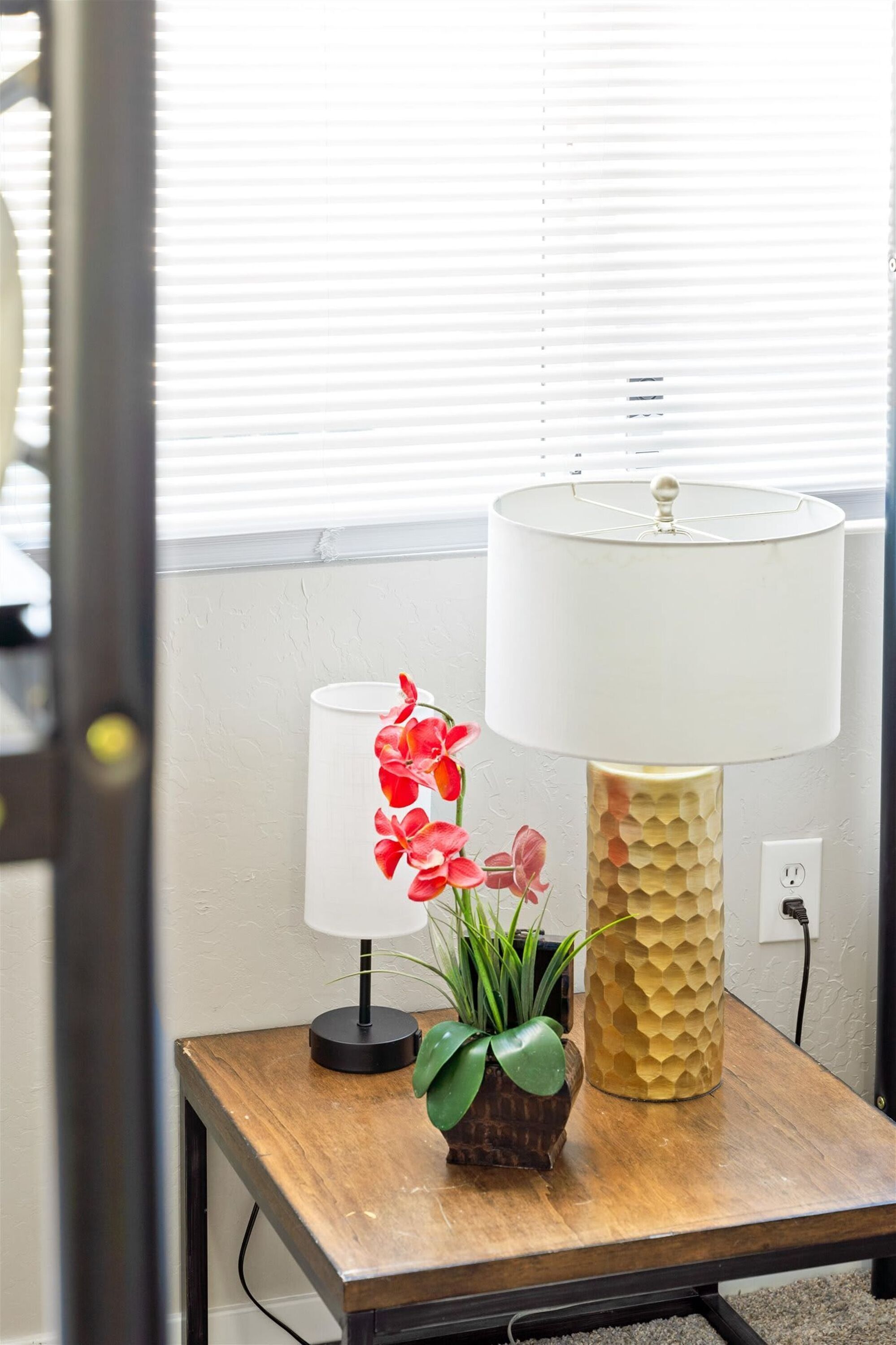 Une table avec une lampe, une plante en pot et un objet décoratif.