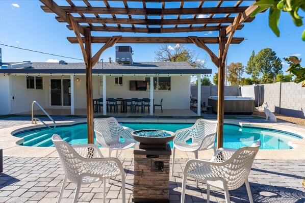 Zona de piscina con pérgola, mobiliario exterior y jacuzzi.