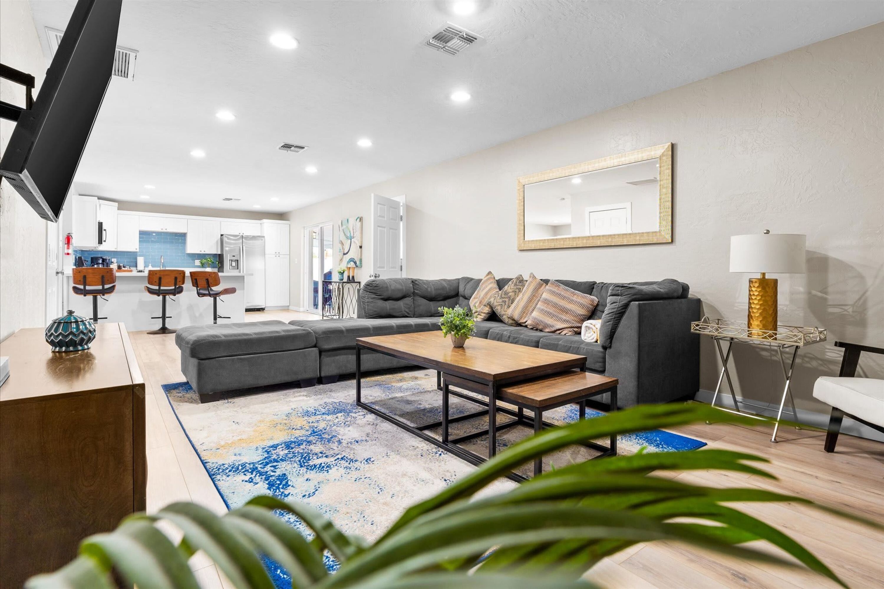 A modern living room with a grey sofa, coffee table, and a TV mounted on the wall.