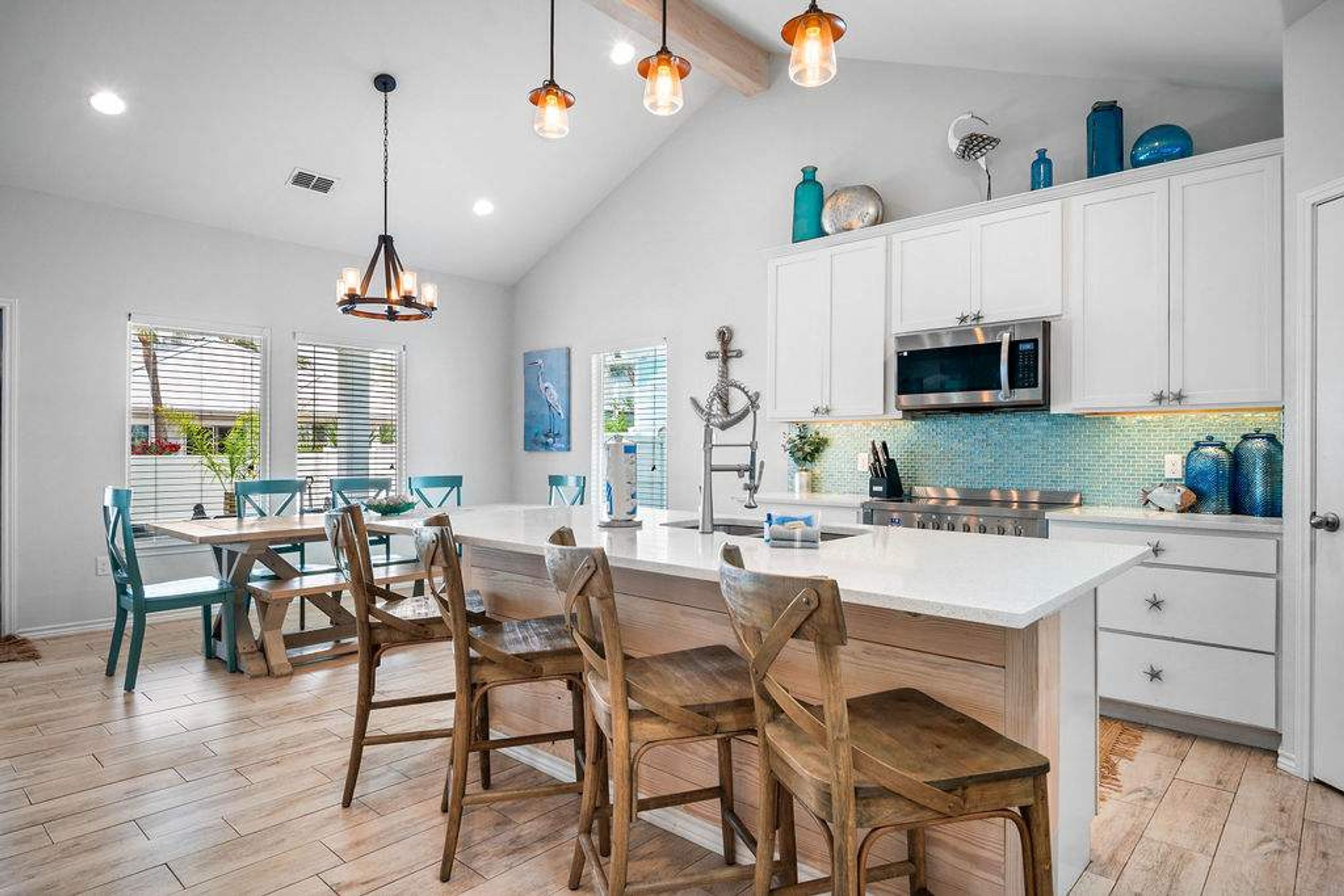 Une cuisine moderne avec des meubles blancs, un grand îlot central et des luminaires suspendus.