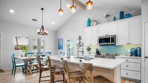 Una cocina moderna con gabinetes blancos, una isla grande e iluminación colgante.