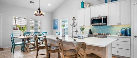 A modern kitchen with white cabinets, a large island, and pendant lighting.